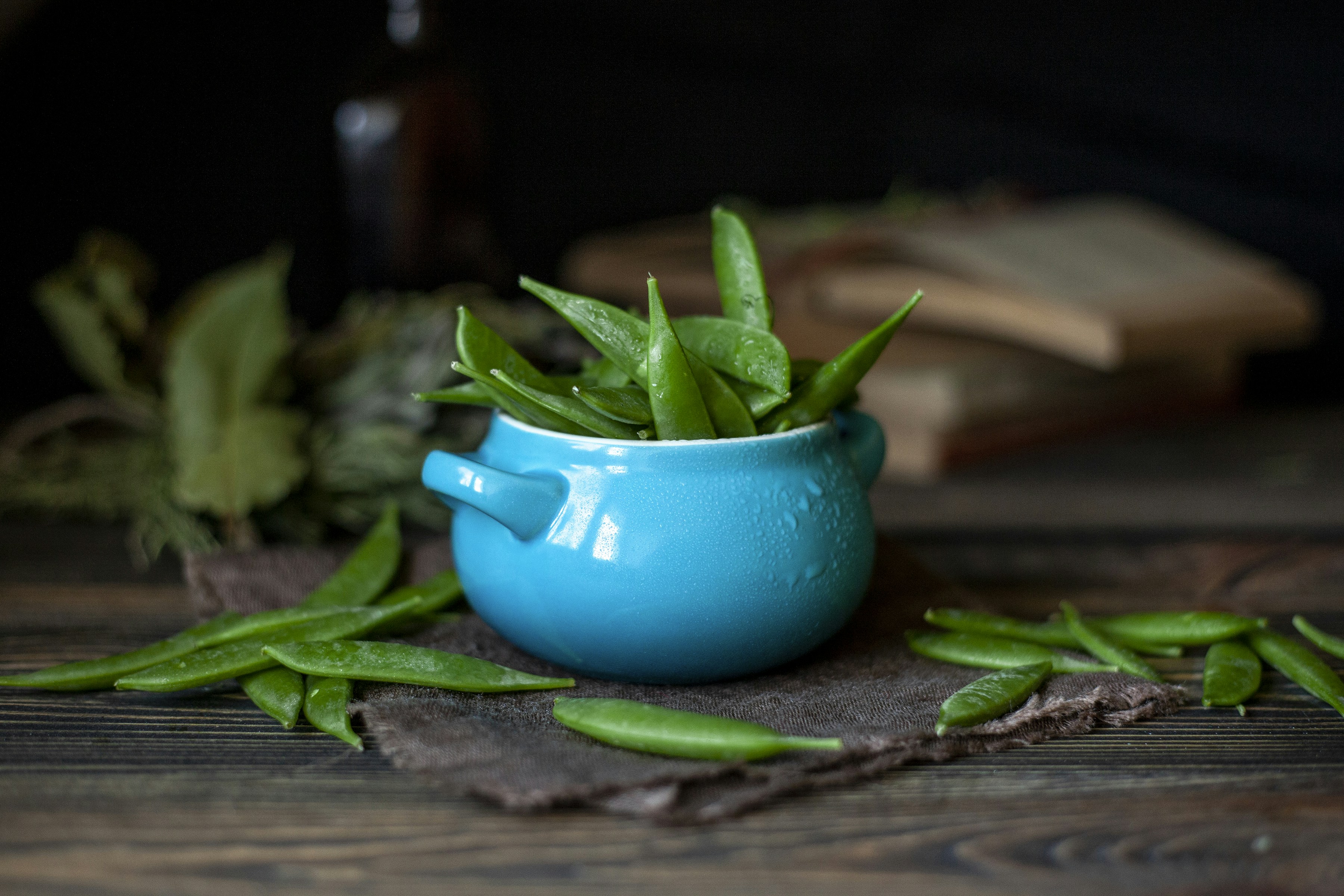 Bright green snap peas in a wooden bowl with farm background