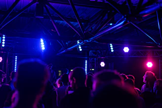 Dark industrial rave scene with intense lighting and crowd immersed in music.