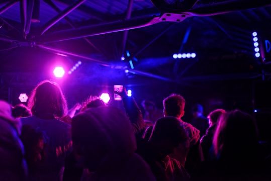 A dynamic group of diverse influencers capturing behind-the-scenes content together, surrounded by vivid purple and electric blue lighting.