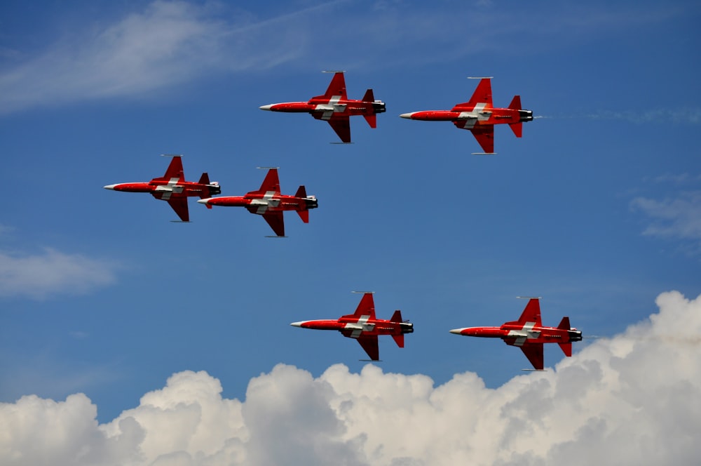 a group of red airplanes flying in the sky