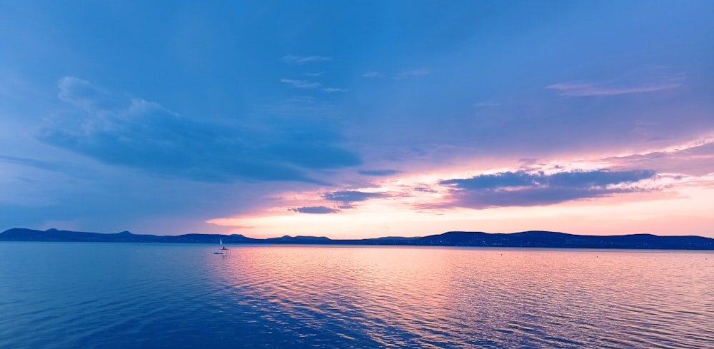 a body of water with a boat in it and a blue sky above