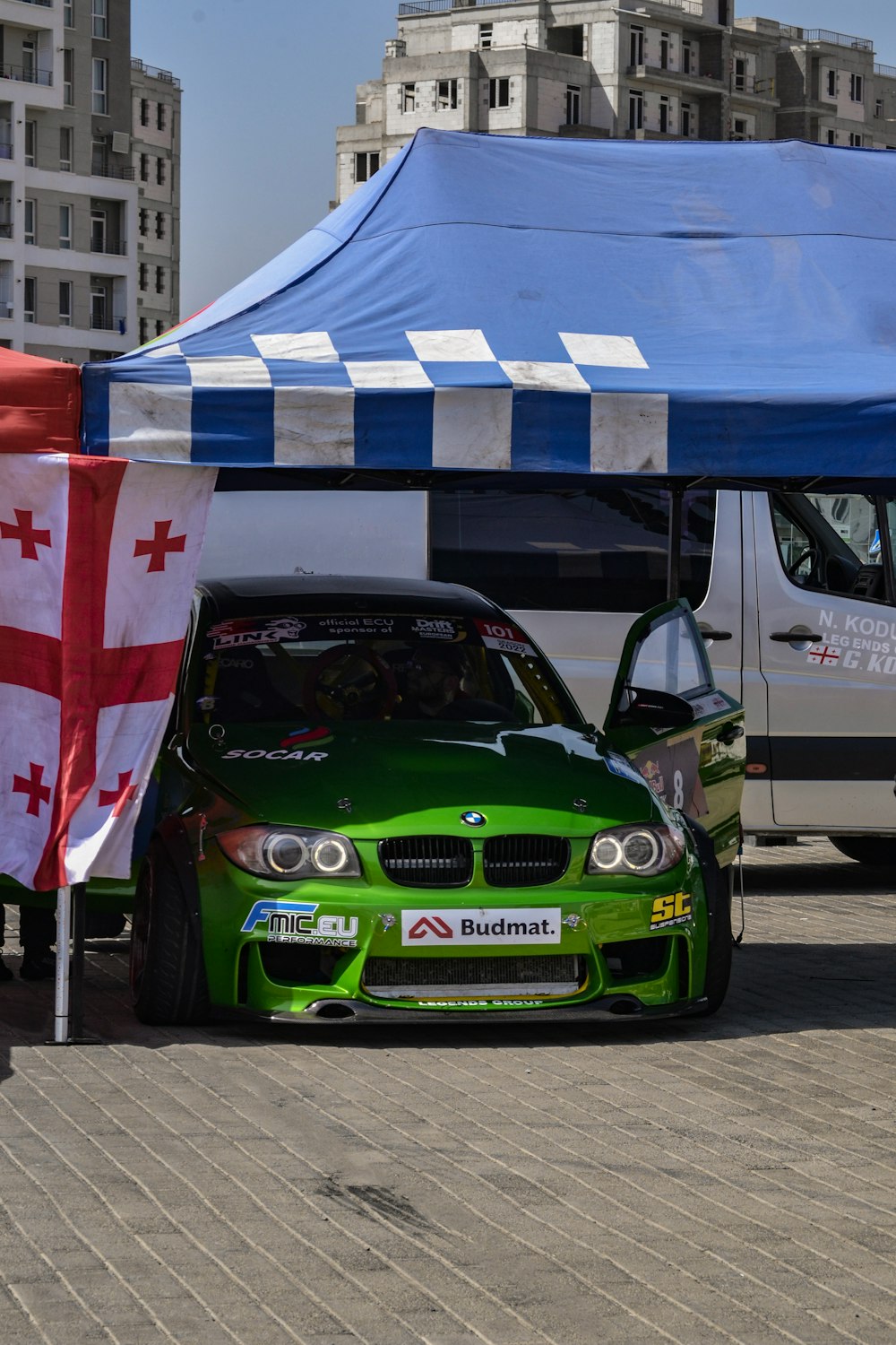 a green car parked in front of a blue and white tent