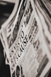 A close-up of a newspaper page with a prominent headline. The text is printed in black and white, and the layout includes columns of articles and an image depicting a person and a public scene. The newspaper appears slightly tilted.