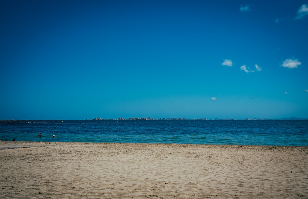 uma praia de areia com um corpo de água no fundo