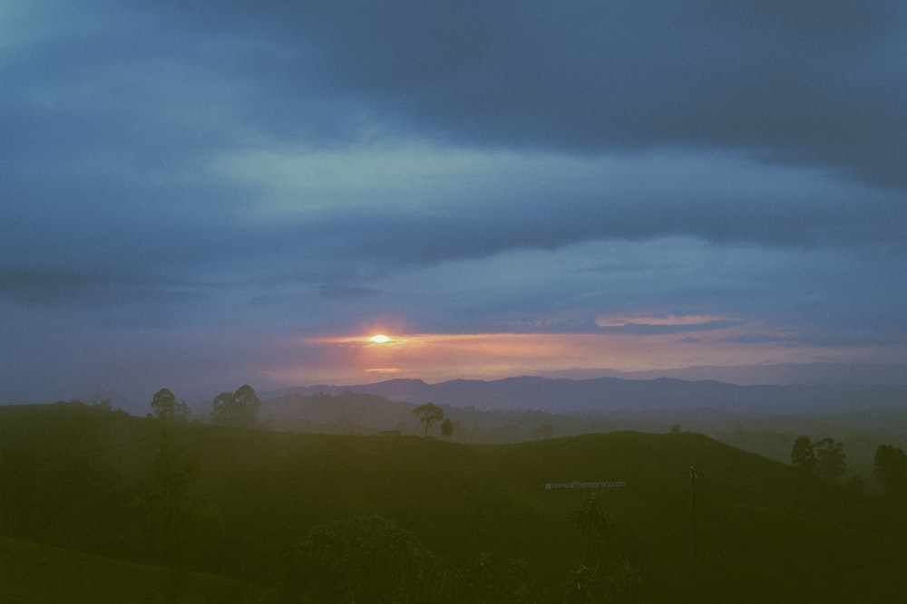 a landscape with trees and a sunset