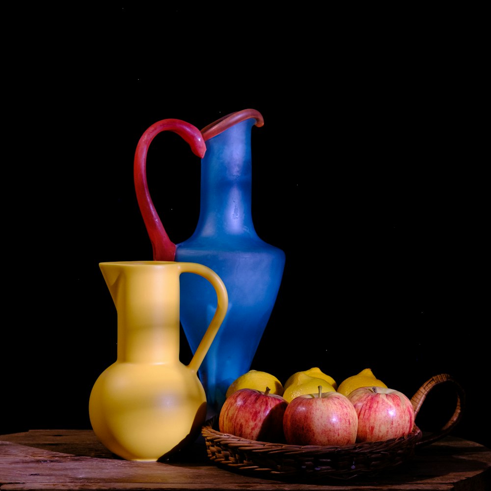 a blue pitcher and some apples