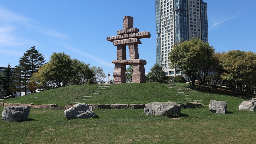 a stone structure in a grassy area with trees and buildings in the background