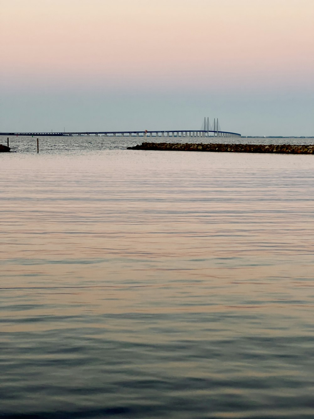 a body of water with a dock and a land with a structure in the distance