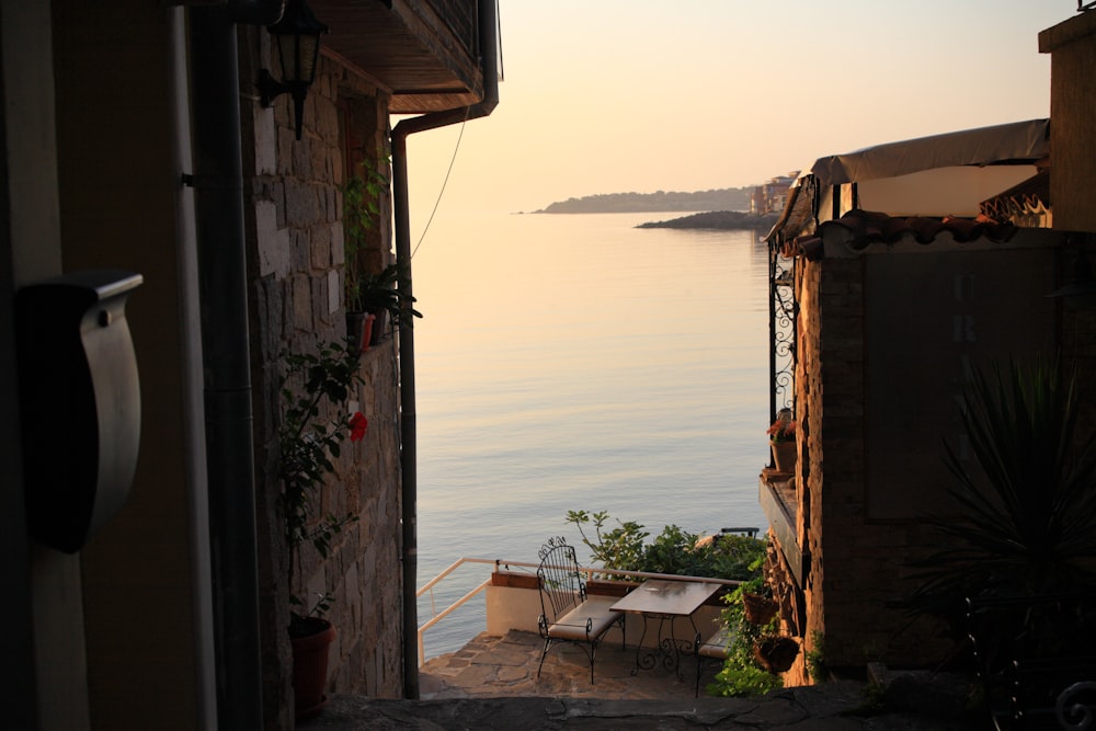 a patio with tables and chairs by a body of water