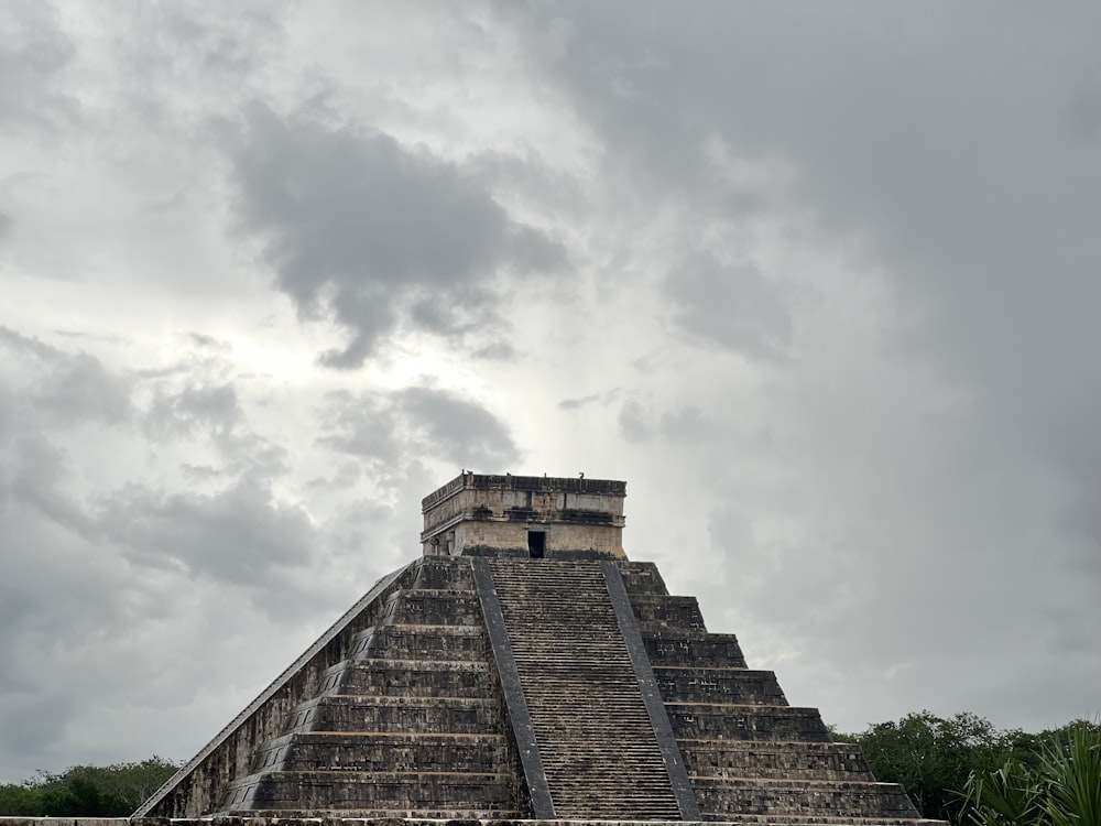 a stone pyramid with a cloudy sky