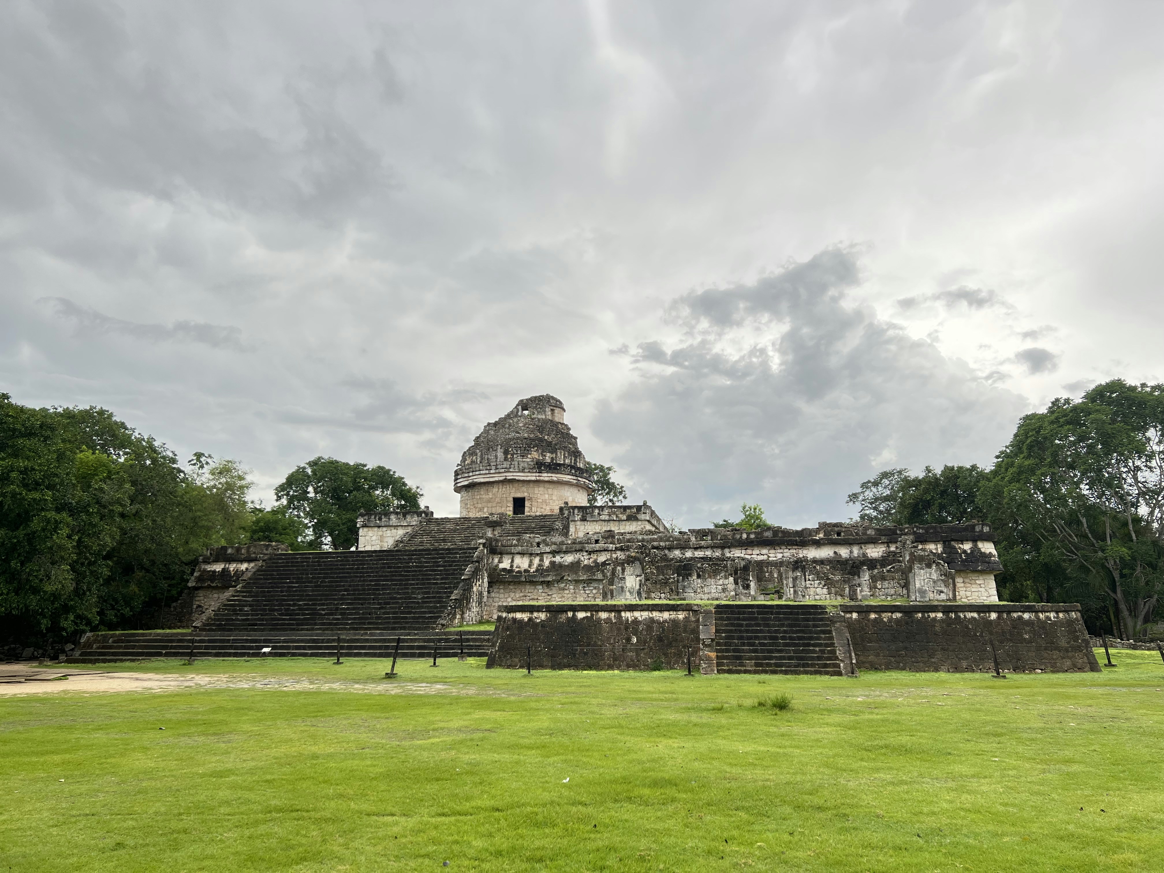 ein großes Steingebäude mit Treppe mit Chichen Itza im Hintergrund