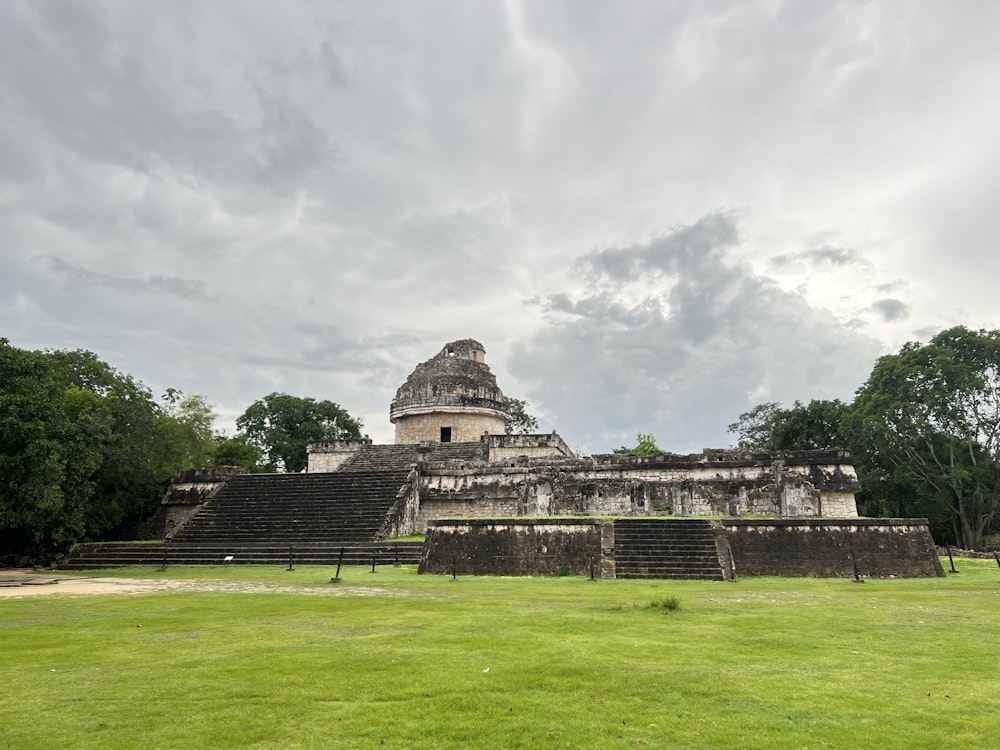 a large stone building with stairs with Chichen Itza in the background