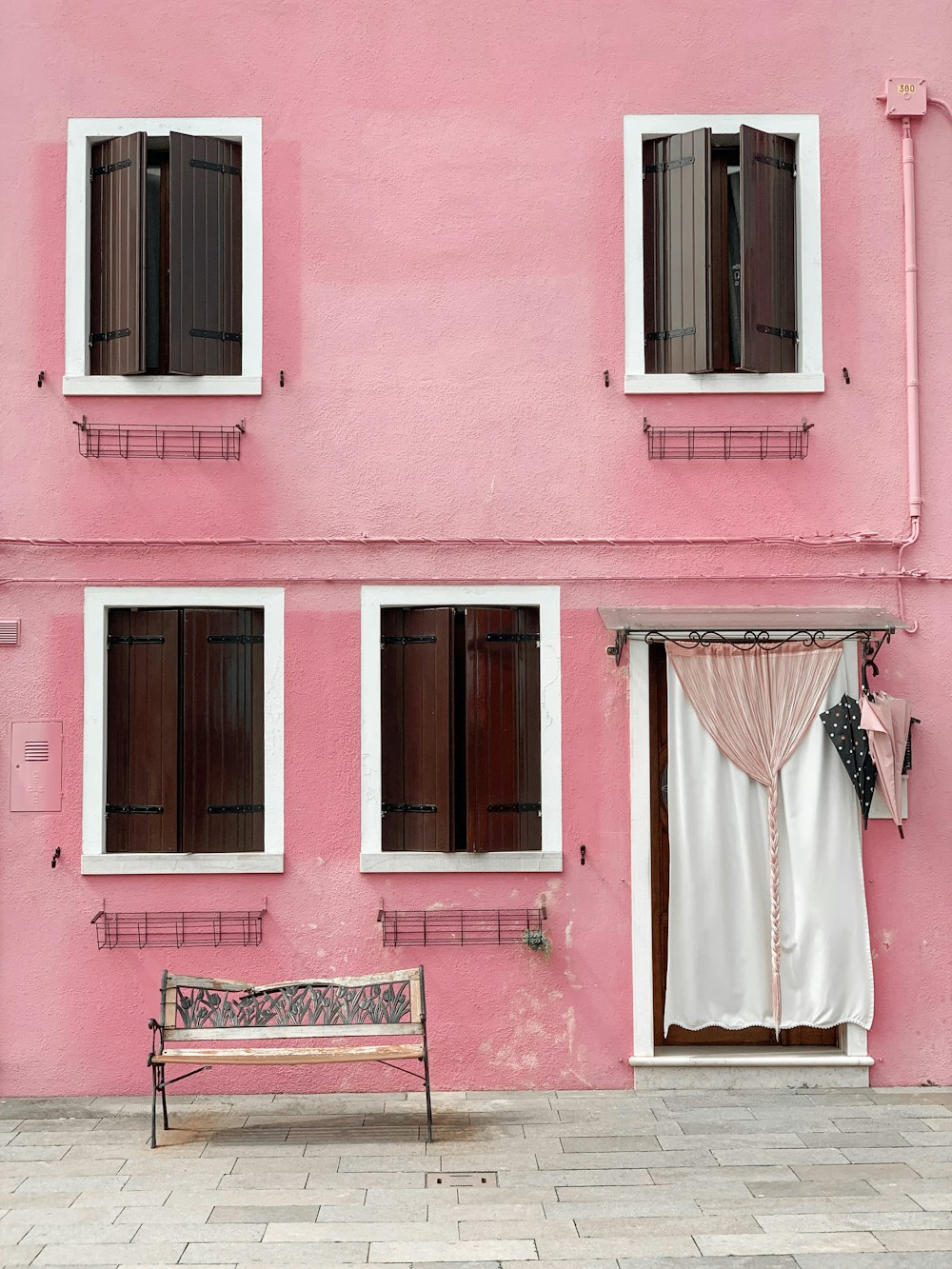 a bench in front of a pink building