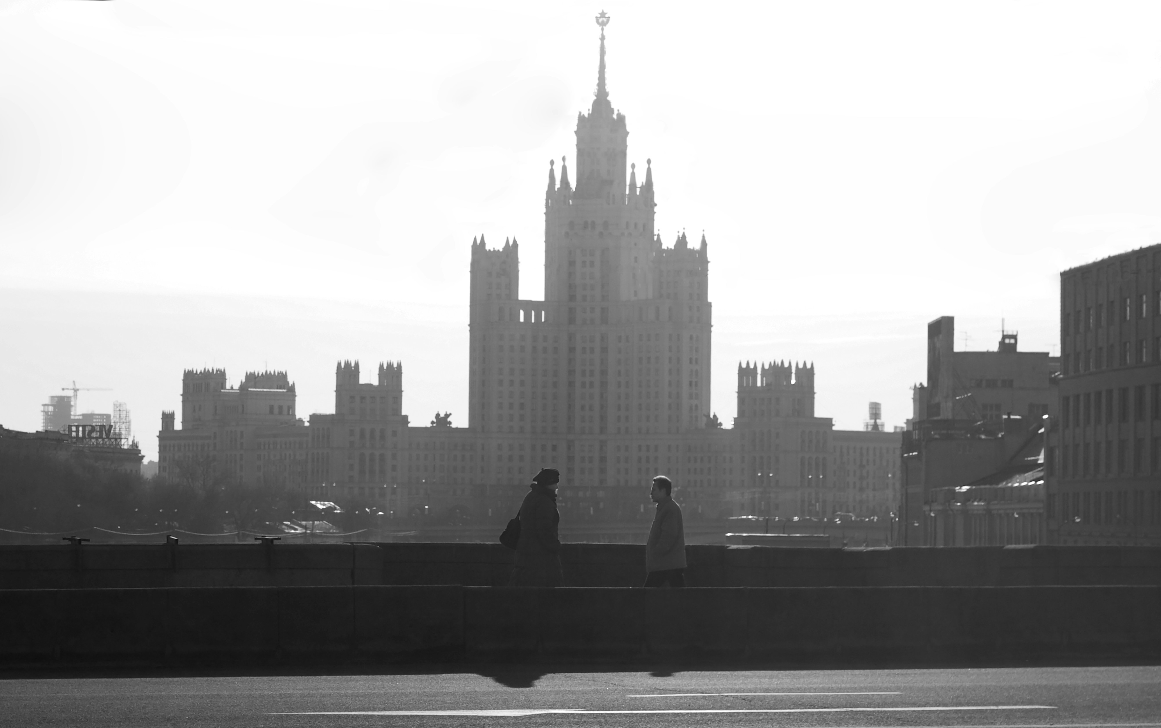 a man and a woman standing on a bridge in front of a large building