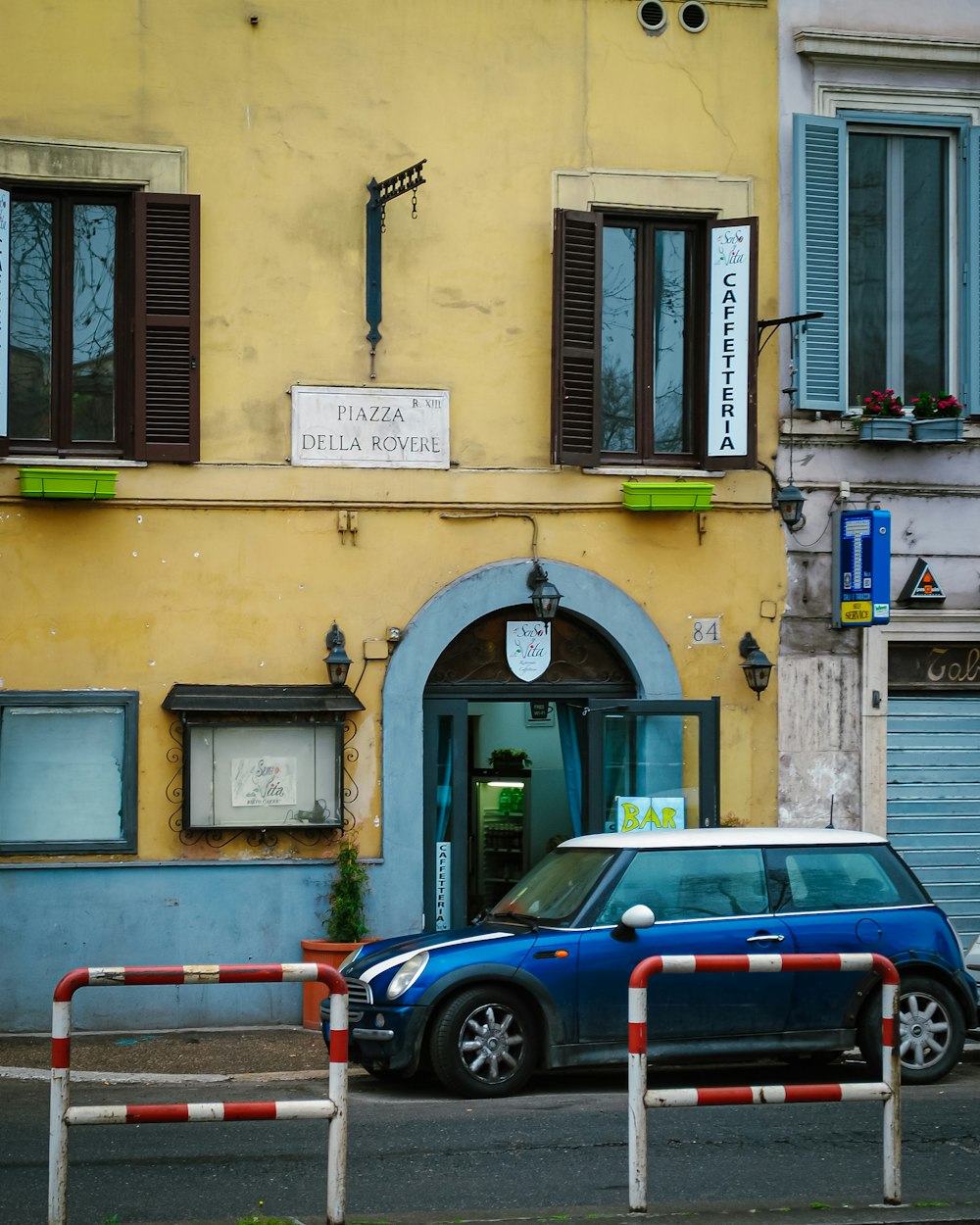 a blue car parked in front of a yellow building