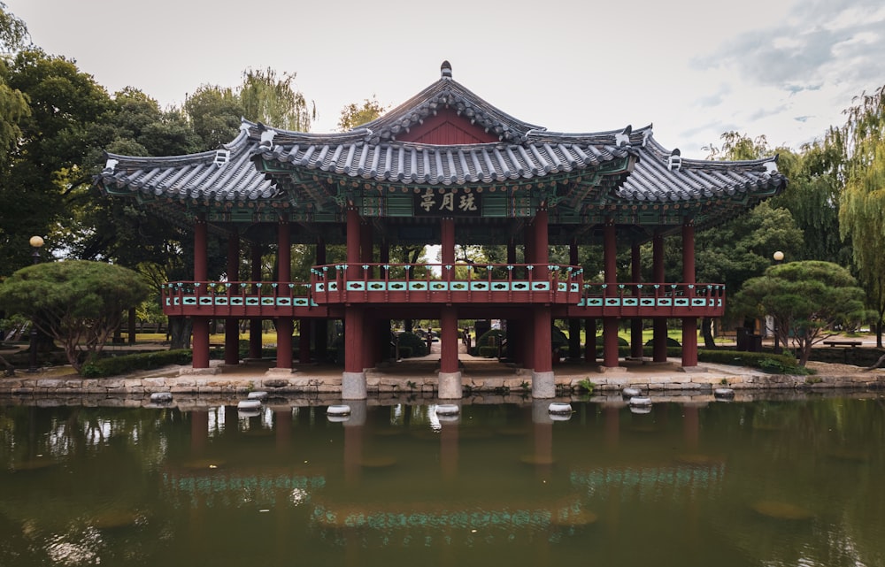 a red asian building with a bridge over water