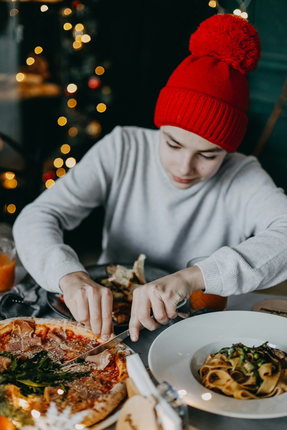 a person in a santa hat cutting a pizza