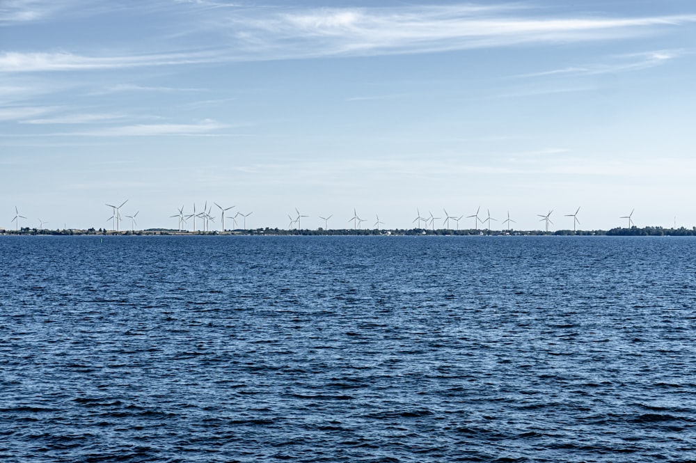 a body of water with a row of wind turbines in the distance