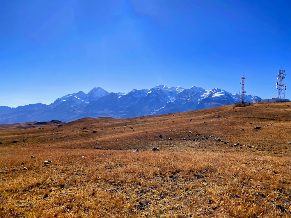 a field with a tower in the distance with mountains in the background