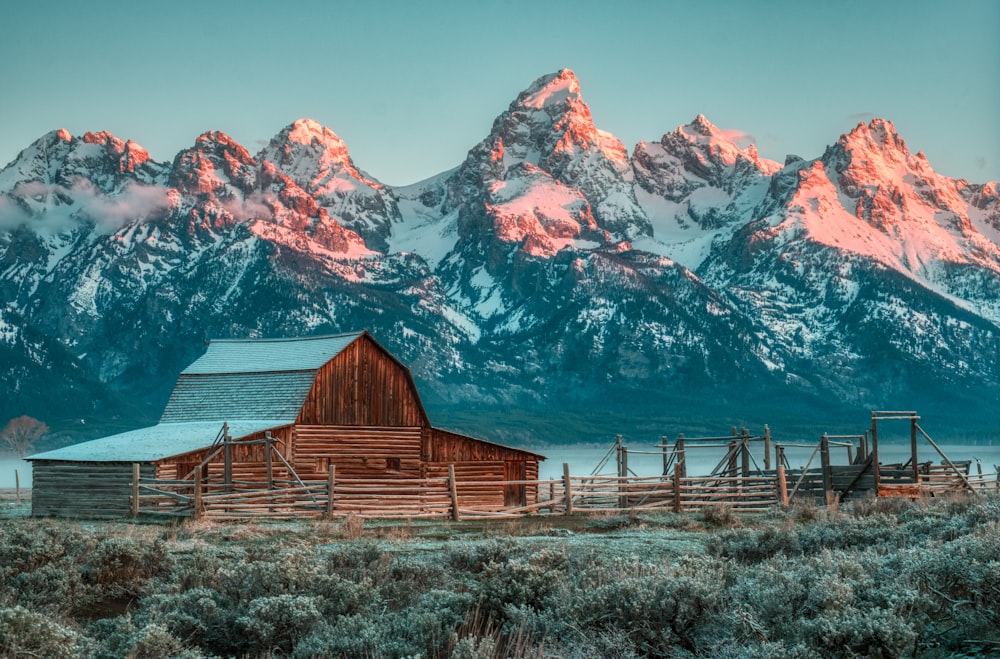 a barn in front of a snowy mountain range