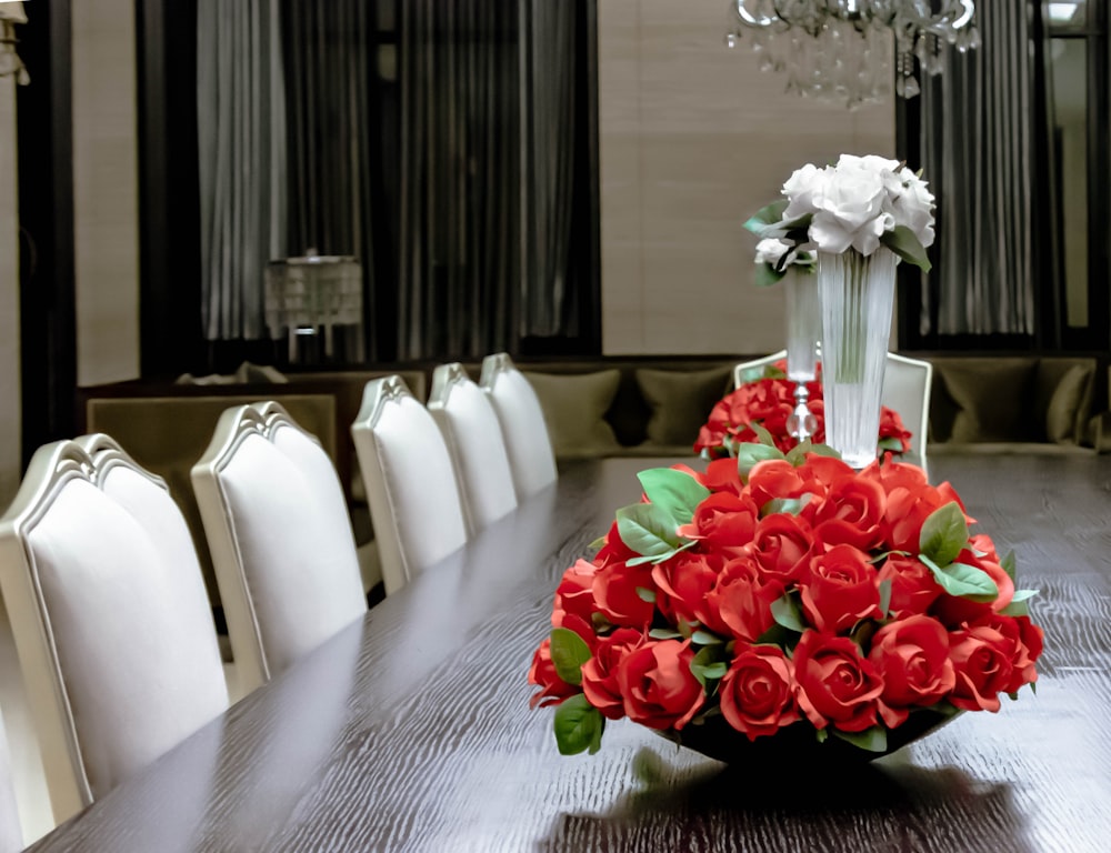 a table with white chairs and red flowers