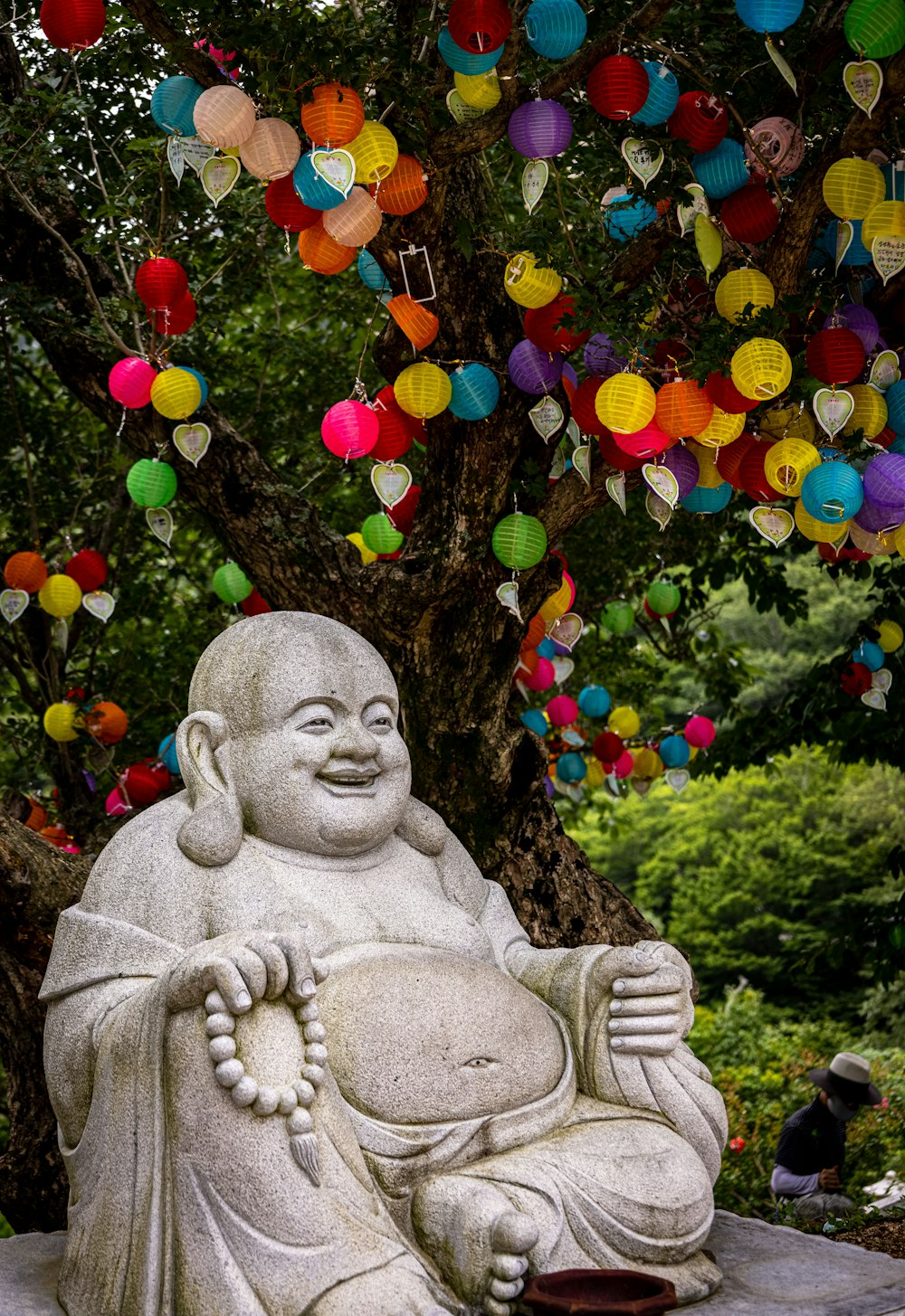 a statue of a person under a tree with colorful ornaments