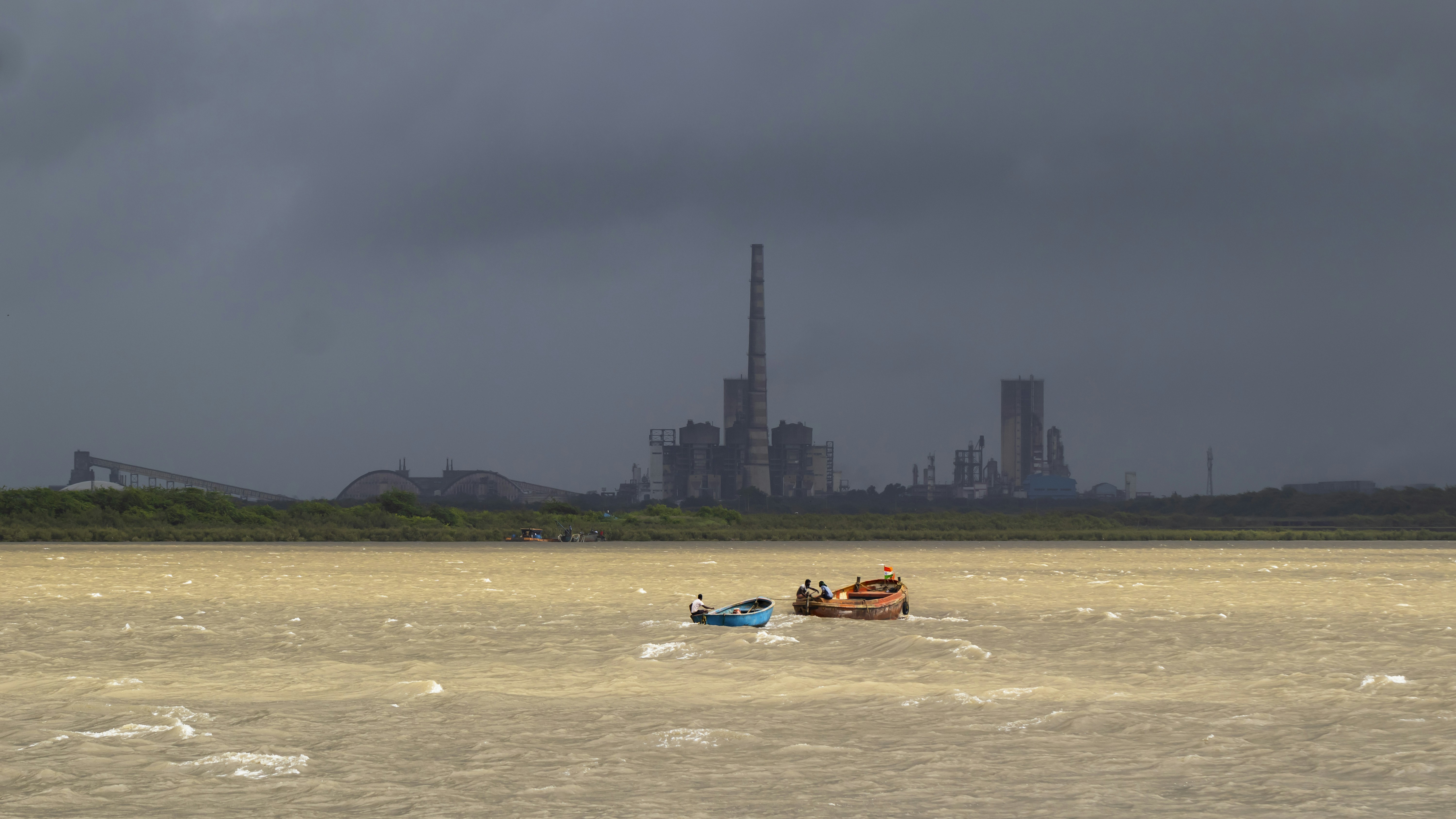 工場を背景にした水域のボートの数隻