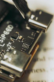 Compact microcontroller units with visible pins and ports, illuminated softly in a dark tech setting.