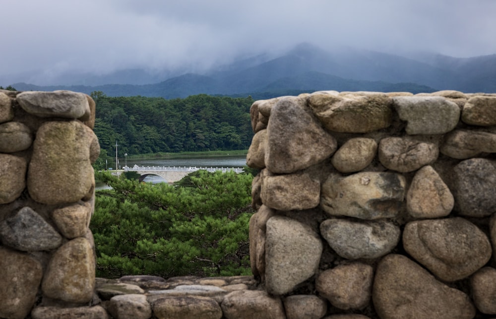a stone wall with a view of a lake and mountains