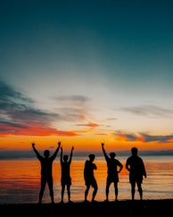 An artistic shot of a group of friends laughing naturally at an outdoor party at sunset.