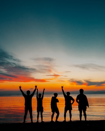 A group photo of friends smiling and waving goodbye at sunset.