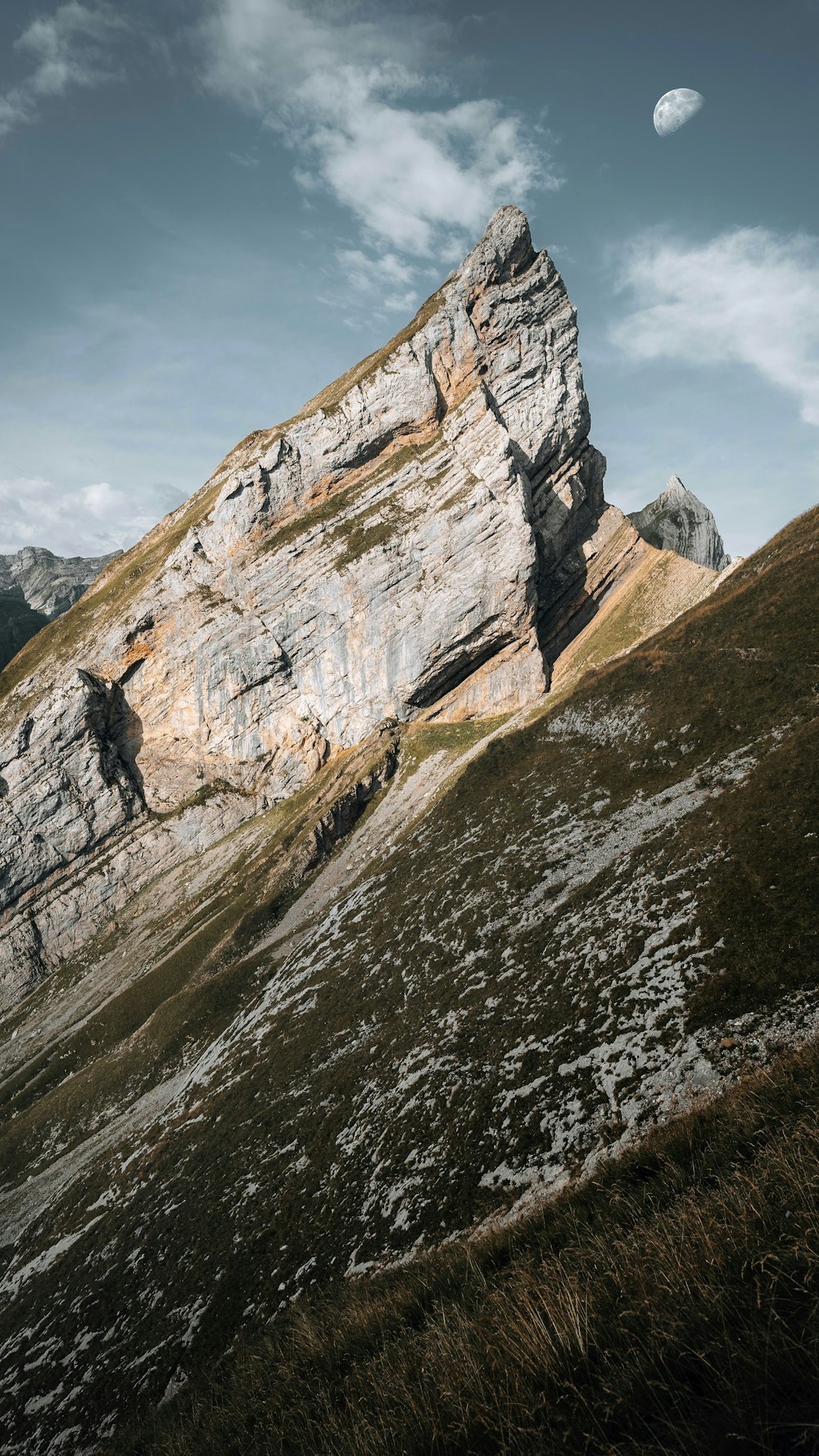 a rocky cliff with a moon in the sky