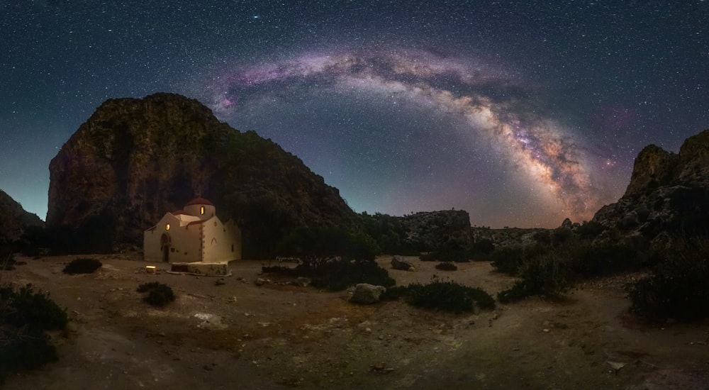 a house on a rocky hill with a starry sky above