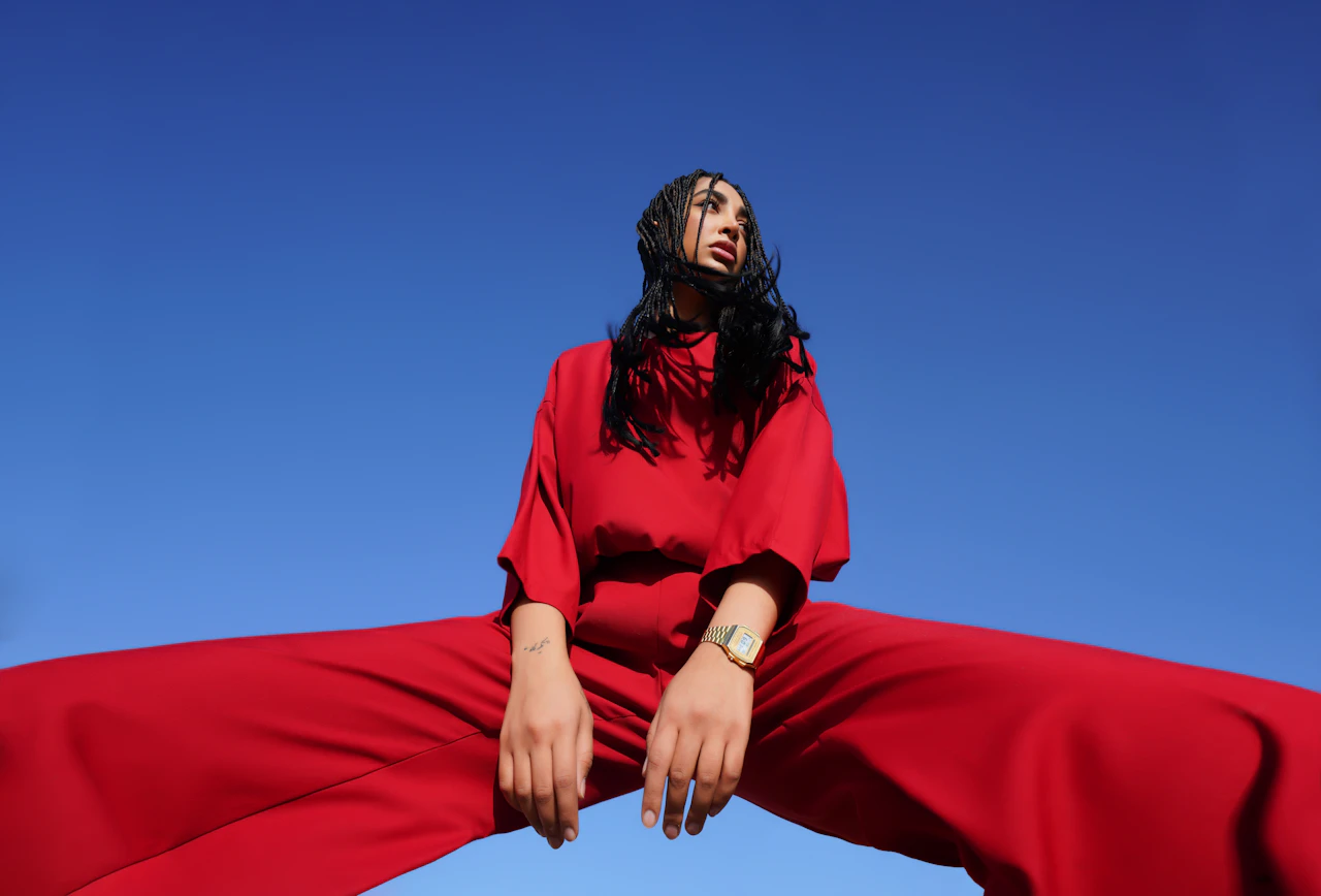 Modelo con conjunto rojo sentada contra un cielo azul despejado