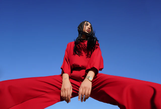 Figure in a flowing red outfit photographed low against open sky