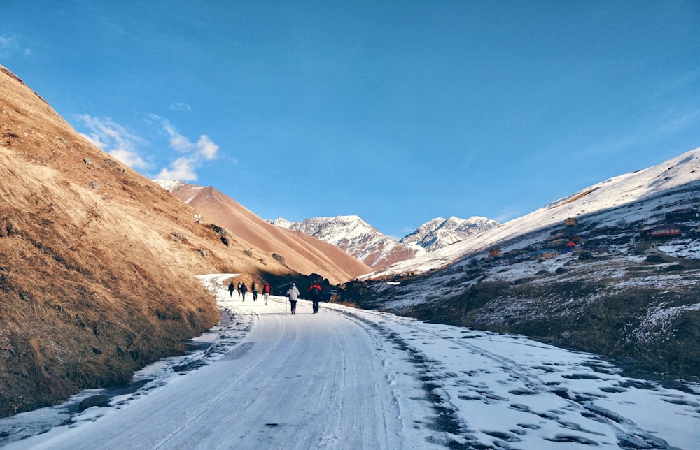 a group of people walking on a snowy road in the mountains