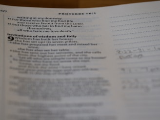 Pages of an open book showing text on one side and lined paper with handwritten notes on the other. The text contains biblical verses and mentions wisdom and folly.