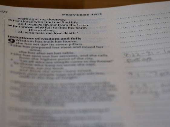 Pages of an open book showing text on one side and lined paper with handwritten notes on the other. The text contains biblical verses and mentions wisdom and folly.
