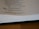 A page from a book is open, showing text from the Proverbs of Solomon. It includes a verse about the joy and grief brought by a wise or foolish son to his parents. The page is partially blurred and the book is lying on a wooden surface.