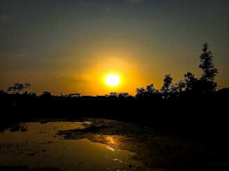 The sun setting behind Nature's Villa, casting a warm glow over the lush lawn.