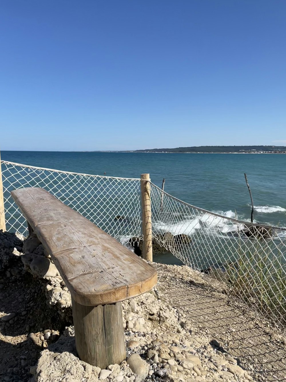 a bench sits on a rocky beach