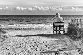 A serene beach accessible by wheelchair, with a rainbow sunset reflecting on calm waves.
