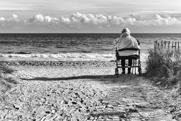 A serene beach accessible by wheelchair, with a rainbow sunset reflecting on calm waves.