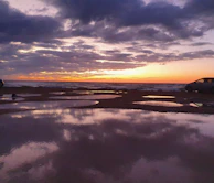 A sunset view with a Can-Am and golf cart parked side by side near the water’s edge.