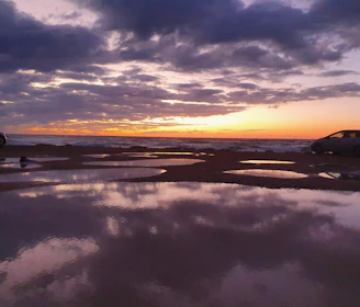 A sunset view with a Can-Am and golf cart parked side by side near the water’s edge.