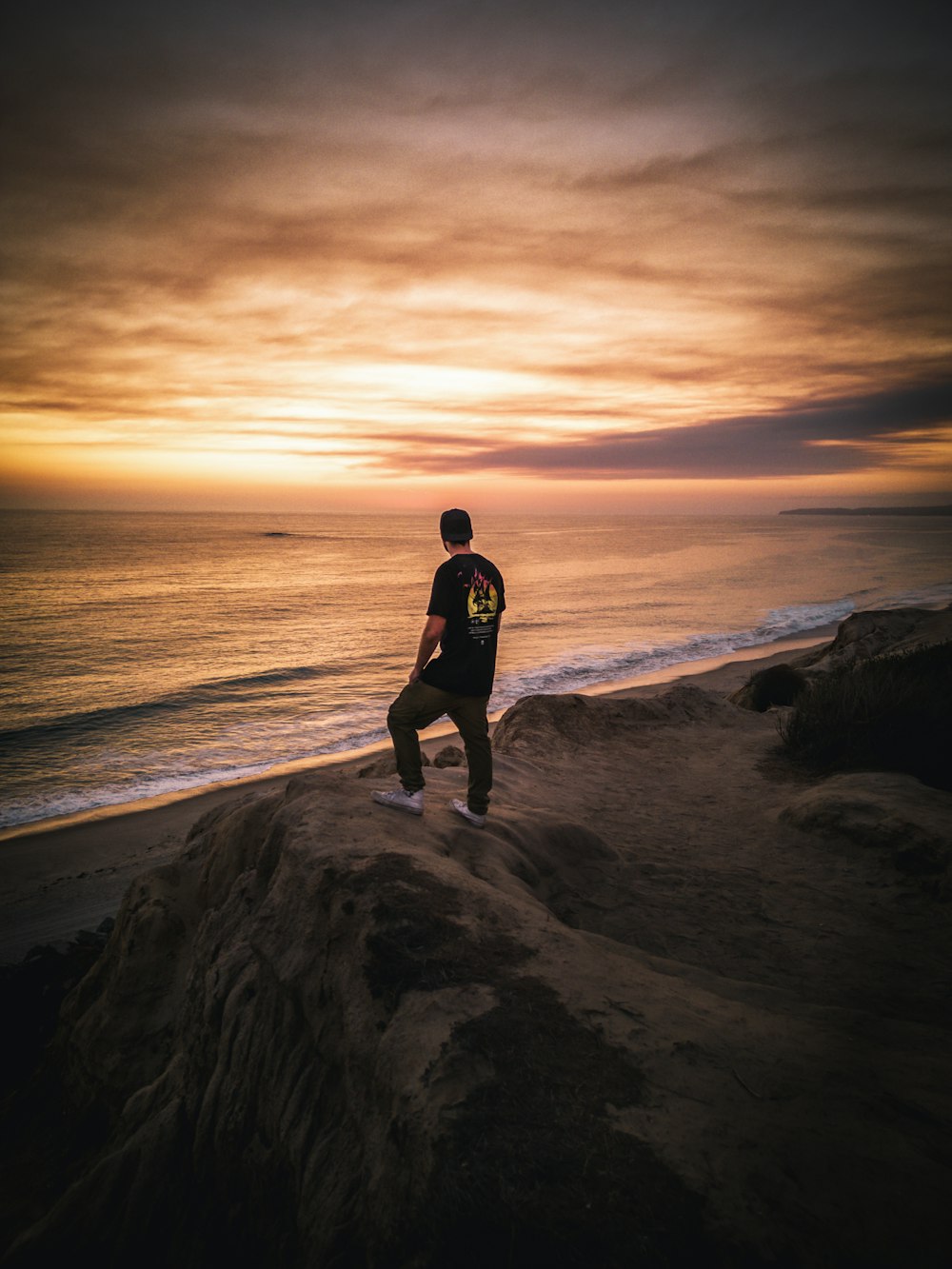 a man standing on a rock looking at the ocean