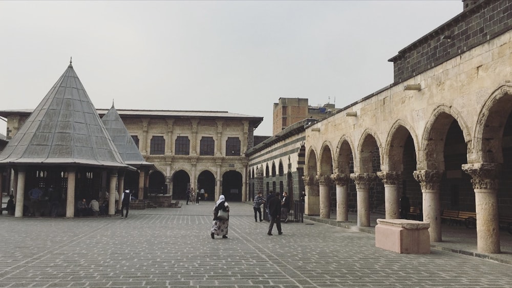 a group of people walking around a courtyard with buildings in the background