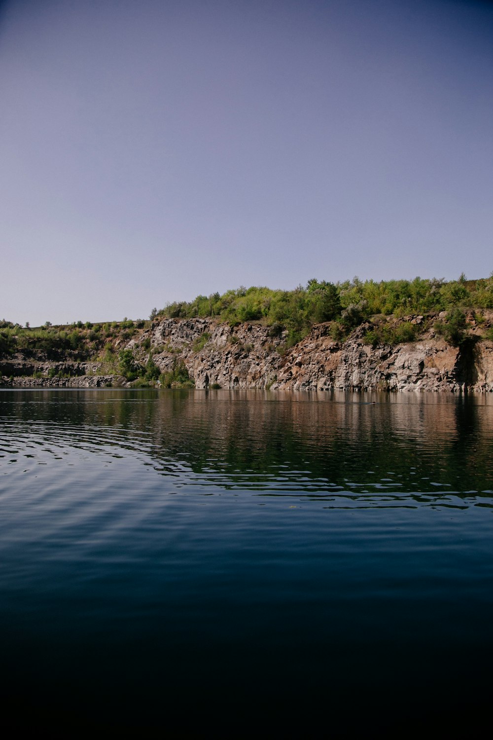 a body of water with a rocky shoreline and trees on the side