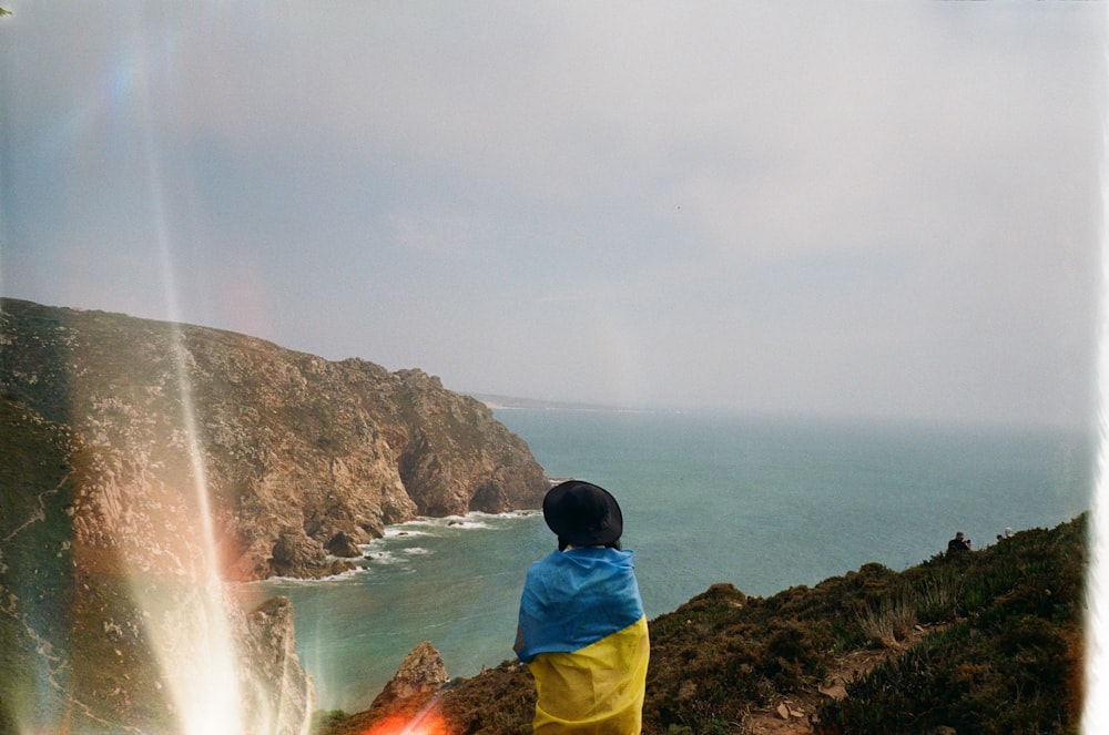 a person standing on a cliff looking at a body of water