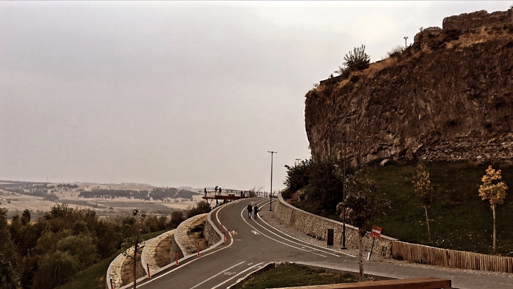 a road with a hill and trees on the side